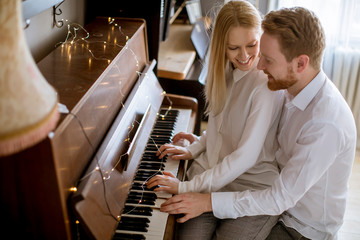Loving young couple playing piano