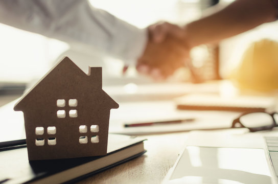 Construction Worker Shaking Hands With Customer After Finishing Up Business Meeting To Start Up Project Contract In Office Center At Construction Site Behind House Model, Home Loan Contract Concept