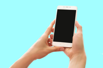 Hands holding smartphone with blank black screen isolated on pastel background
