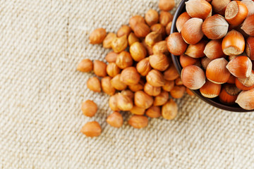 Peeled hazelnuts in a wooden, dark brown cup on a burlap cloth. Super Food, Raw.