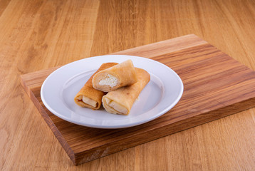 Pancakes with cottage cheese on a plate on a wooden board