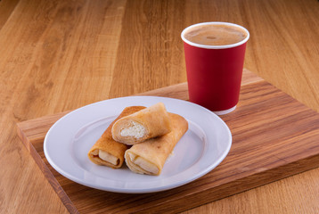 Pancakes with cottage cheese on a plate on a wooden board, is served with a cup of coffee