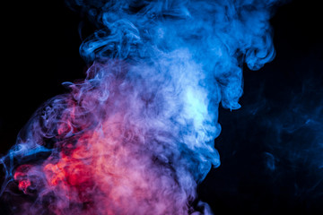 Dense exhaled blue purple and white smoke in the form of a cloud on a black background moves smoothly into the dissolving vapor column from the vape.