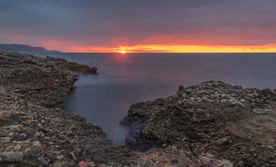 Nerja, Malaga, Andalusi, Spain - November 25, 2018: Long exposure on the coast with a rocks in the foreground under a stormy sky