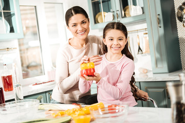Pleased brunette female embracing her charming daughter
