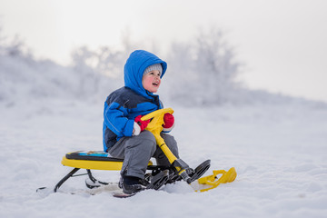 a small child is sitting on a snow scooter in winter