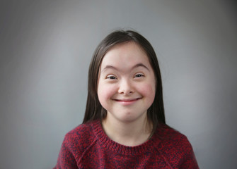 Cute smiling down syndrome girl on the grey background