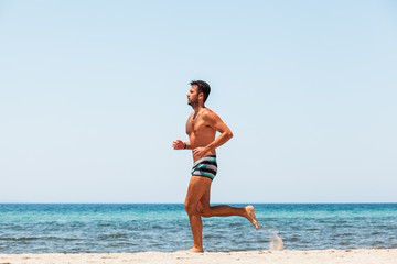 Young handsome man running on the beach