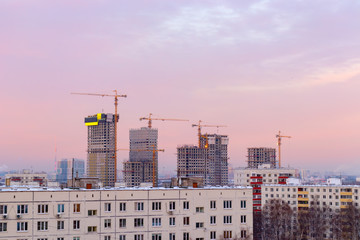Fototapeta na wymiar City landscape at dawn, sunrise with beautiful skyline and buildings under constructions with cranes. Urban landscape in the morning