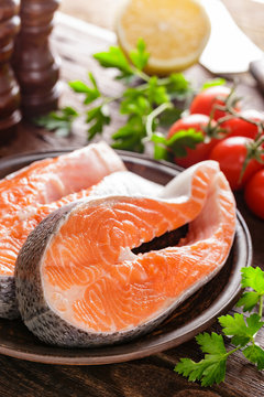 Cooking two fresh raw salmon fish steaks on wooden rustic table closeup