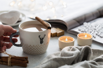 Cup of cacao, marshmallow, warm knitted sweater on grey background. Warm lights. Cozy winter. Lifestyle concept. Lifestyle rustic nordic concept
