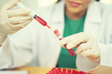 hand of a lab technician or medical doctor holding syringe drops of blood tube test and background...