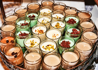 Numerous dessert glasses filled with coffee cream and panna cotta, filled with candied fruit and coffee beans