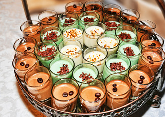 Numerous dessert glasses filled with coffee cream and panna cotta, filled with candied fruit and coffee beans