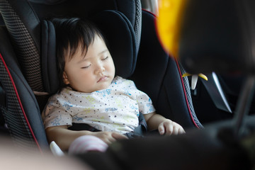 Asian women Mother takes care about her daughter in a car, helps her child fasten little young baby with car seat safety belt for infant,parent is keeping safe when riding in a vehicle on road.
