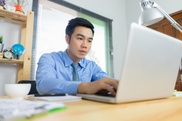 Asian young businessman working with laptop in coffee shop cafe while drinking coffee ,technology or startup business concept, modern office or living room with copy space