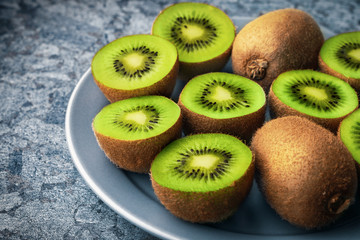 Sliced kiwi fruit in a gray plate on a stone table