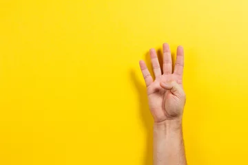 Fotobehang Man hand showing four fingers on yellow background. Number two symbol © vejaa