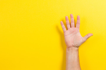 Man hand showing five fingers on yellow background. Number two symbol