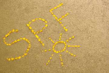 Sun protect factor SPF word written on the sand. Skin care concept background