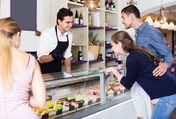 Happy seller helping friends to choose sweets