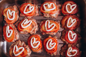 Wooden white background with cutlets and tomatoes with hearts on top. The concept of Valentine Day. Romantic dinner concept