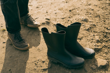 Feets and clean boots at muddy ground
