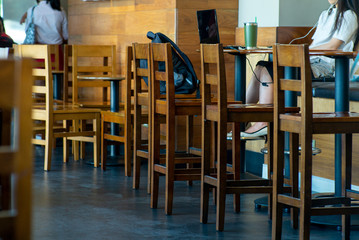 Selective focus on vintage wooden furniture with a woman working with her notebook in the coffee shop