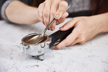 Fototapeta na wymiar fresh black coffee preparation concept, woman's hands on white plywood background