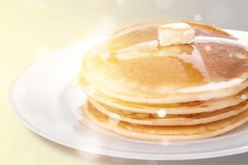 Stack of tasty pancakes with butter on a white plate