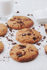 Homemade chocolate chips cookies with salt on small plate and glass of milk on white background, top view. Food styling shot