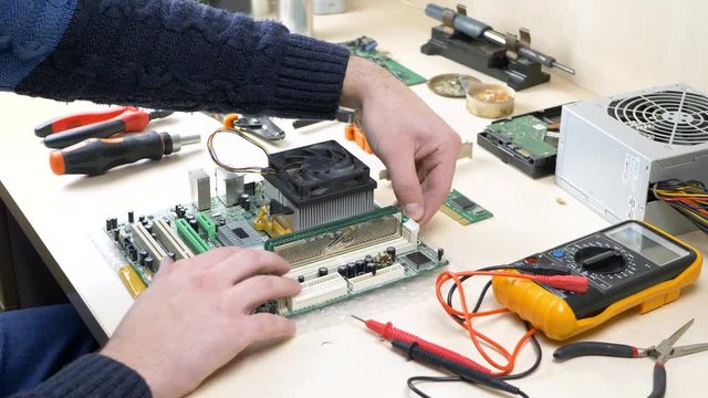 Hand repairing computer and working with RAM memory on PC motherboard in electronics workshop