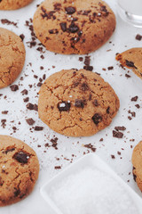 Homemade chocolate chips cookies with salt on small plate and glass of milk on white background, top view. Food styling shot