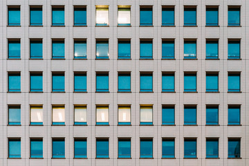 Modern building facade with window glass sky color reflected and some lighted from the inside.