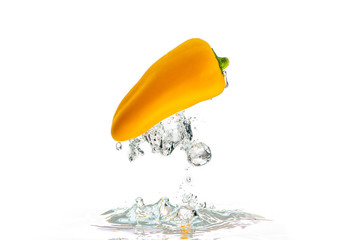 Yellow paprika falls under water with a splash. With lots of air bubbles upside down