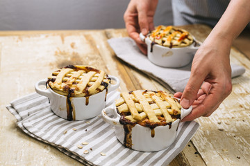 woman holding apple pie on bright wooden table