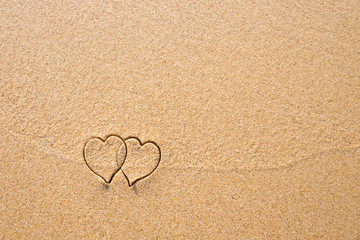 Two hearts drawn in the sand at the beach.