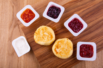  Cheesecakes with orange, raspberry, strawberry, cherry jam and sour cream on a wooden board