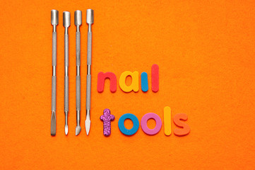 A set of nail tools on an orange background and the word nail tools