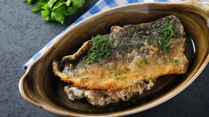 Fried fish fillets with mushrooms, onion and white sauce. Fried carp fillet on a plate.