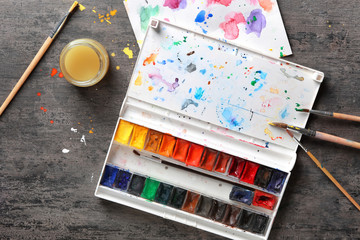 Paint palette with brushes on grey background