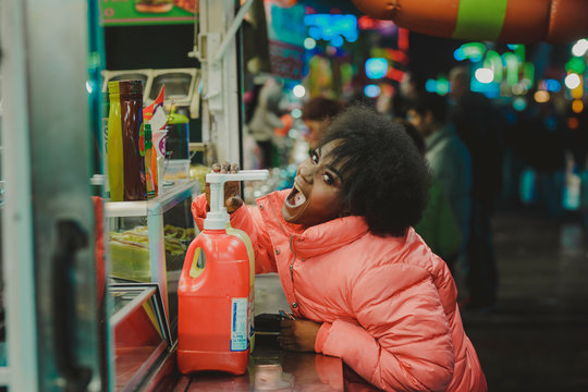 Black woman pretending to eat sauce from diner bottle