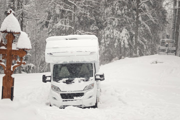 camping car or campervan outdoor on the mountain side offroad near the forest in the winter snowing