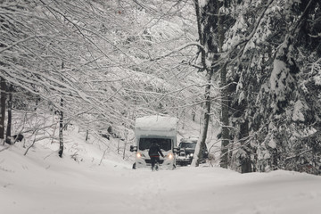 camping car or campervan outdoor on the mountain side offroad near the forest in the winter snowing