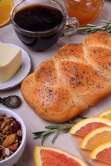 Challah bread, oranges, coffee, granola, butter and apricot jam on the table. Breakfast ingredients
