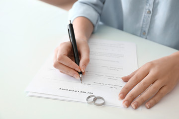 Young woman signing decree of divorce at table, closeup