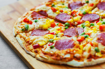 Pizza with vegetables mix, Mozzarella cheese, pepperoni, tomato, salami. Italian pizza on wooden table background