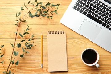 Laptop, notebook, coffee and branch of exotic plant on wooden table