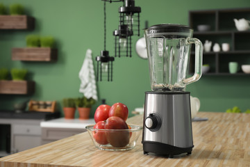 Modern blender with fresh mango on wooden table in kitchen