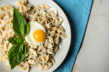 Plate with tasty pasta and fried egg on light table